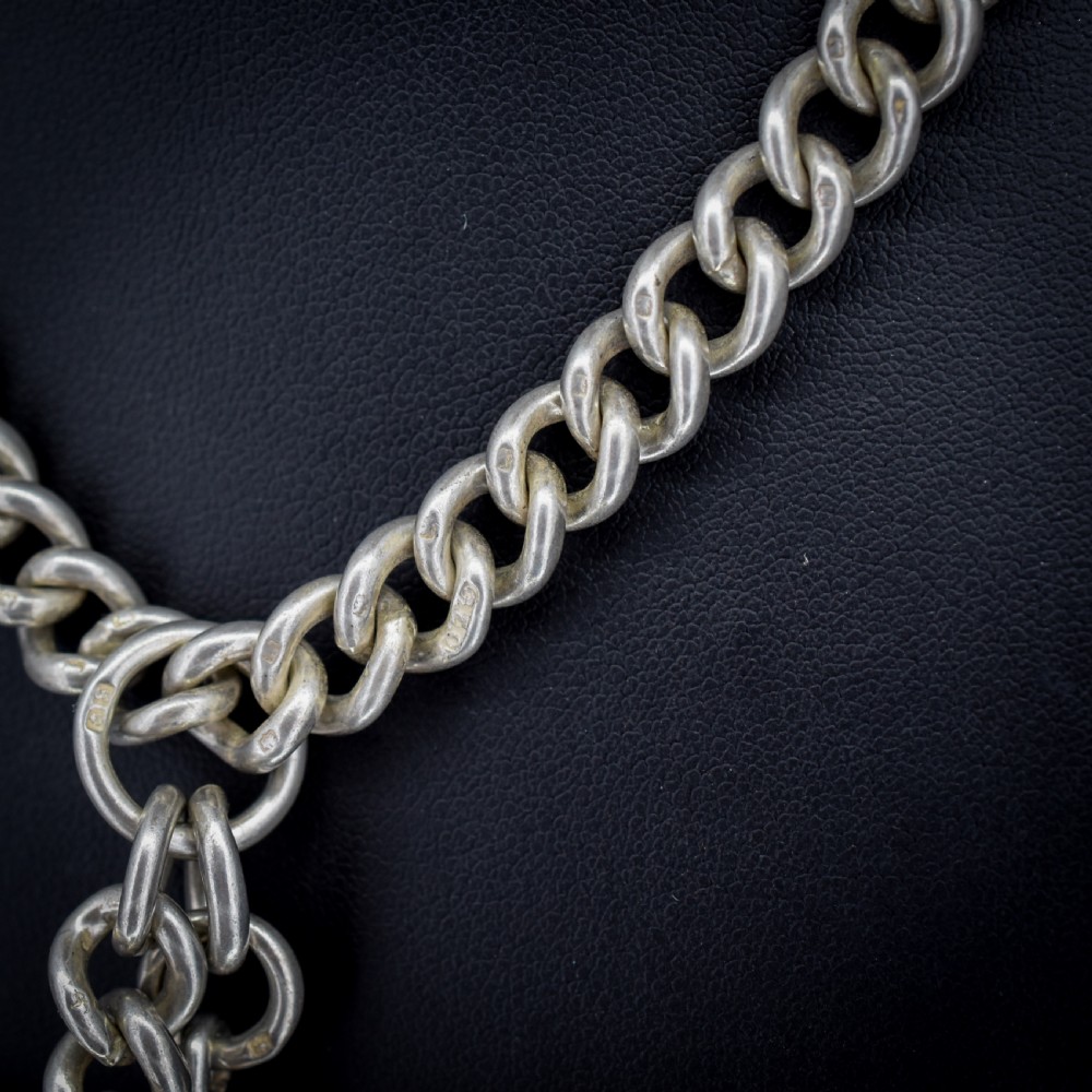 An antique sterling silver curb link Albert watch chain featuring a T-bar and dog clips displayed on blue velvet. View VII