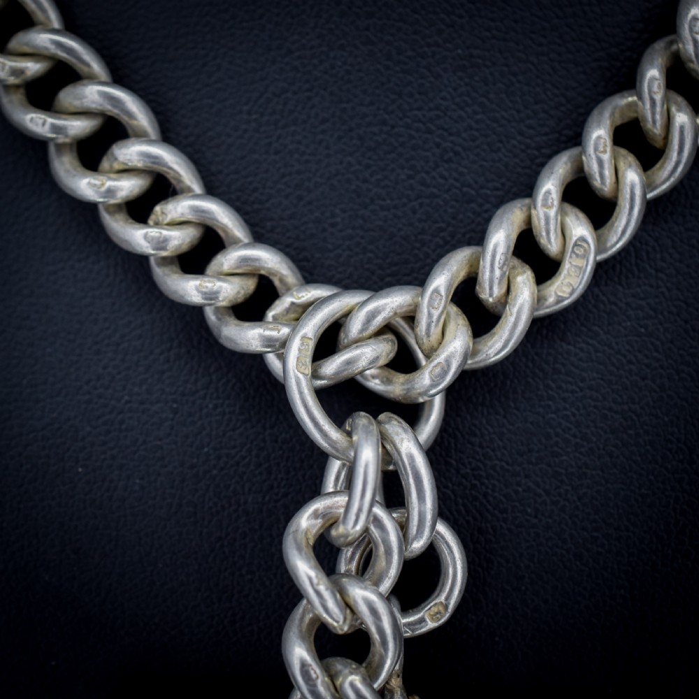 An antique sterling silver curb link Albert watch chain featuring a T-bar and dog clips displayed on blue velvet. View VIII