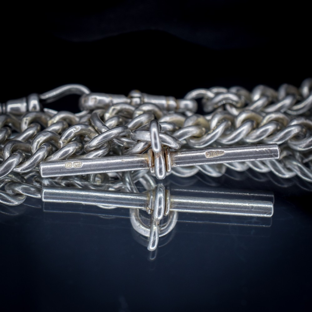 An antique sterling silver curb link Albert watch chain featuring a T-bar and dog clips displayed on blue velvet. View IX