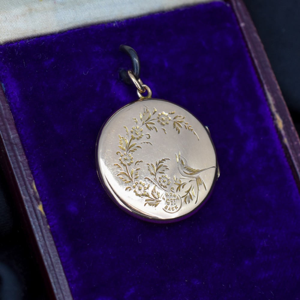 A circular antique yellow gold locket featuring intricate hand engraving of a flower basket motif. View V