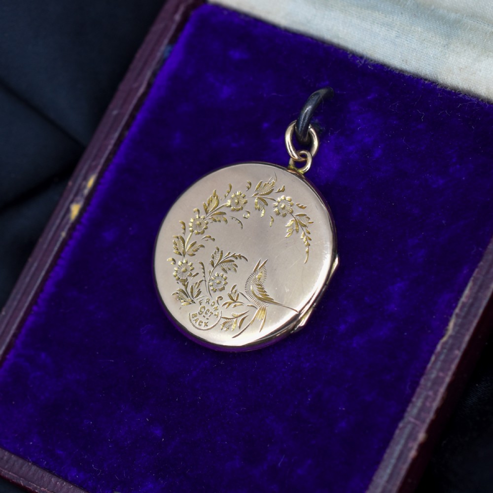 A circular antique yellow gold locket featuring intricate hand engraving of a flower basket motif. View VI