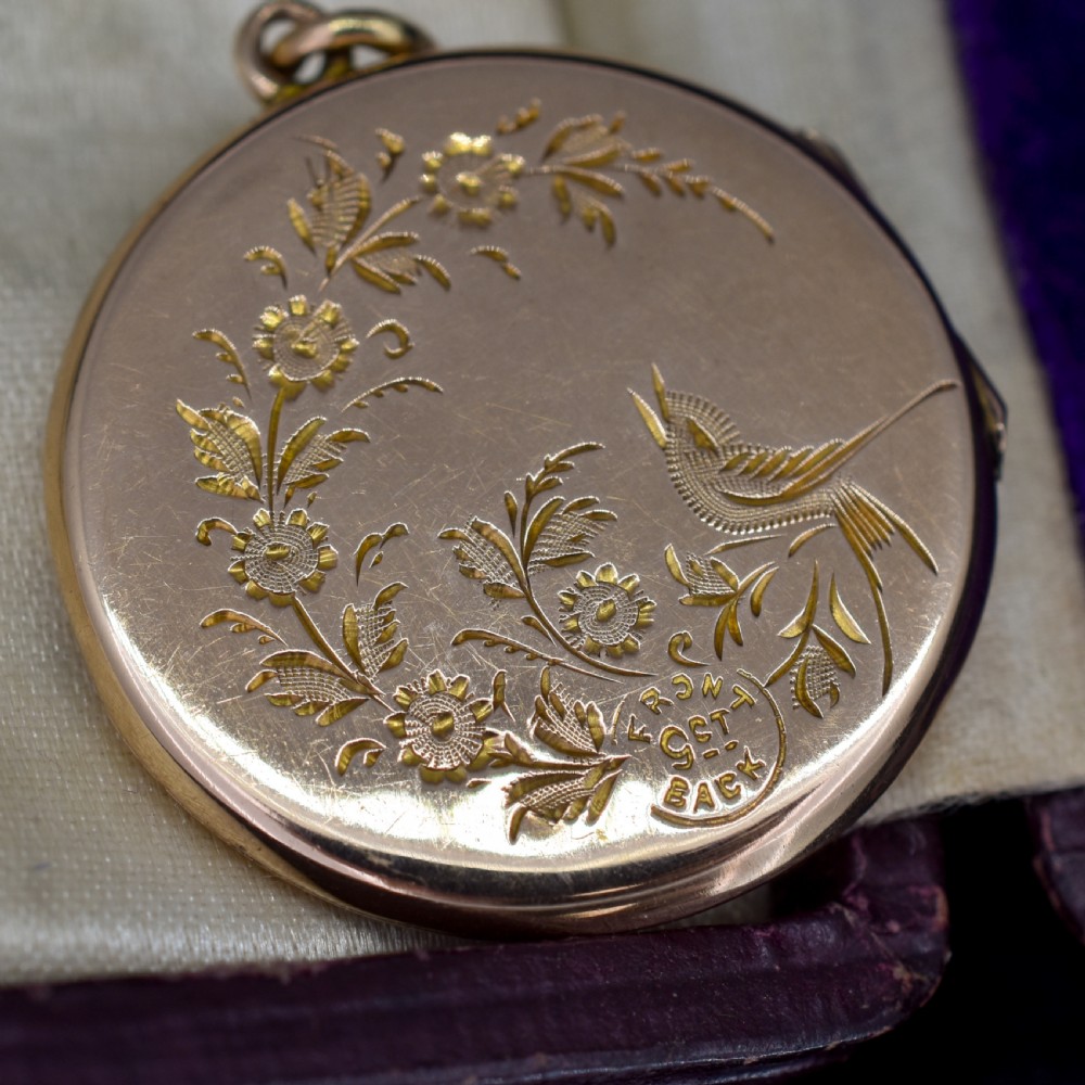 A circular antique yellow gold locket featuring intricate hand engraving of a flower basket motif. View IX