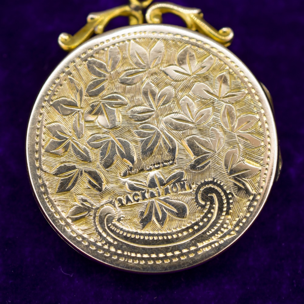 A circular 9ct yellow gold antique locket featuring hand-engraved foliate scrollwork and a central blank shield cartouche with a ornate top loop. View VIII