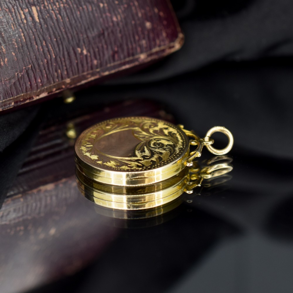 A circular 9ct yellow gold antique locket featuring hand-engraved foliate scrollwork and a central blank shield cartouche with a ornate top loop. View IX