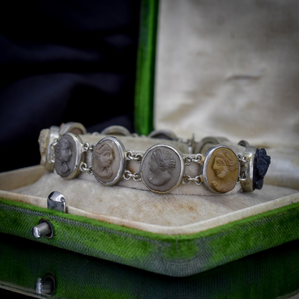 An antique Victorian Grand Tour bracelet featuring oval lava stone cameos carved with classical portrait busts, connected by silver link chains. View V