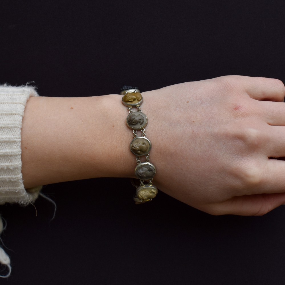 An antique Victorian Grand Tour bracelet featuring oval lava stone cameos carved with classical portrait busts, connected by silver link chains. View VI