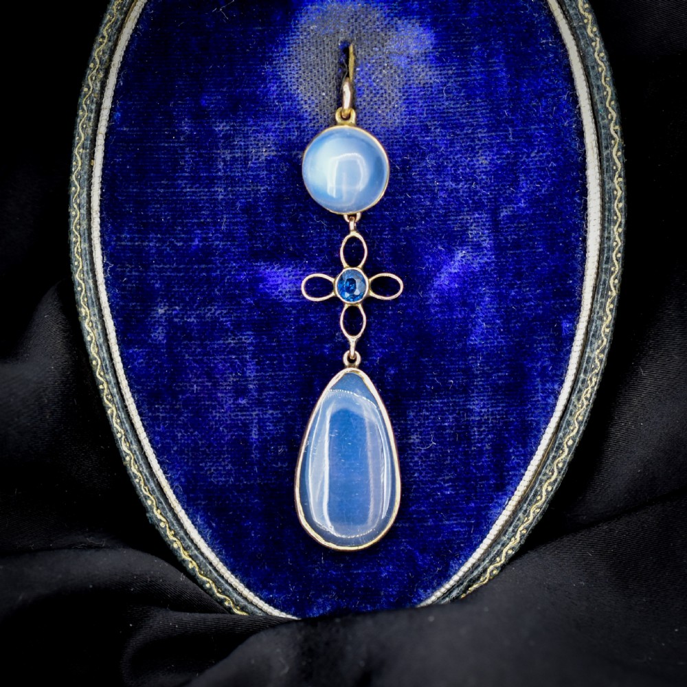 An antique 9ct gold drop pendant featuring a round moonstone cabochon, a centre quatrefoil motif with a blue sapphire, and a teardrop moonstone drop.