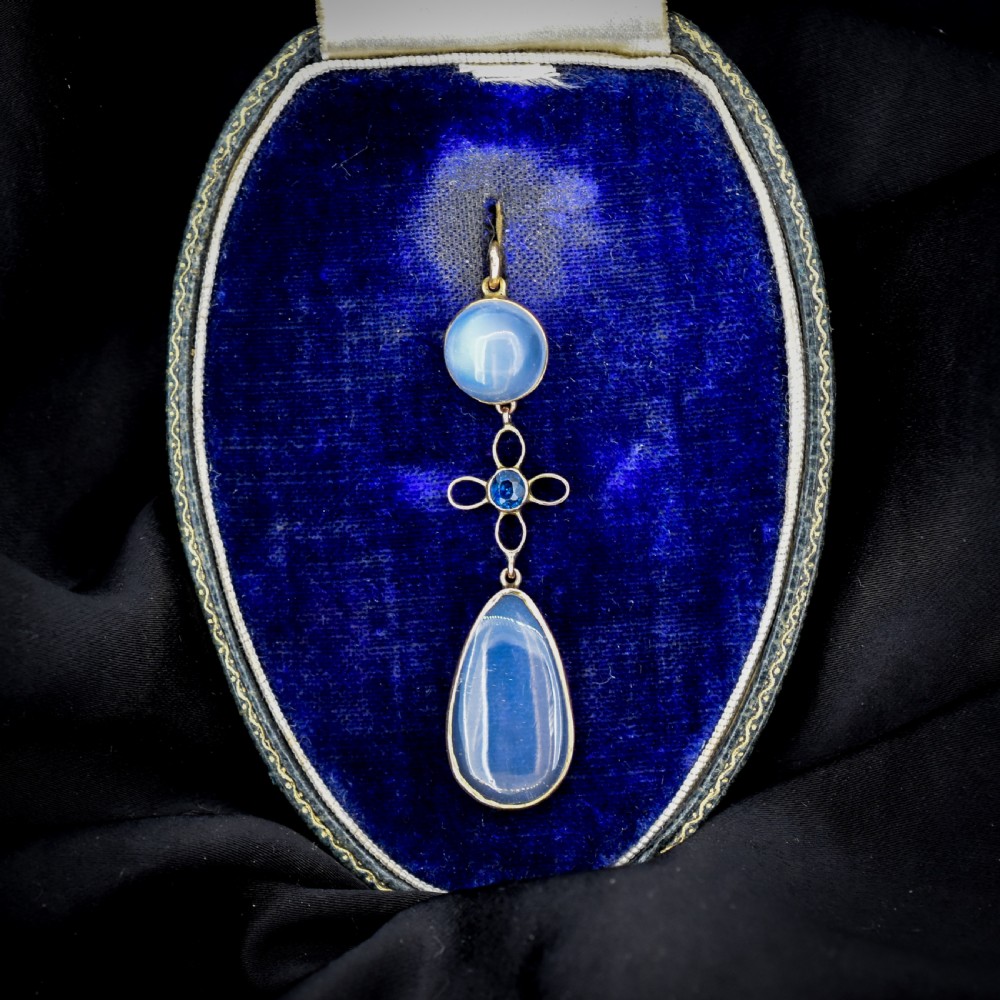 An antique 9ct gold drop pendant featuring a round moonstone cabochon, a centre quatrefoil motif with a blue sapphire, and a teardrop moonstone drop. View III
