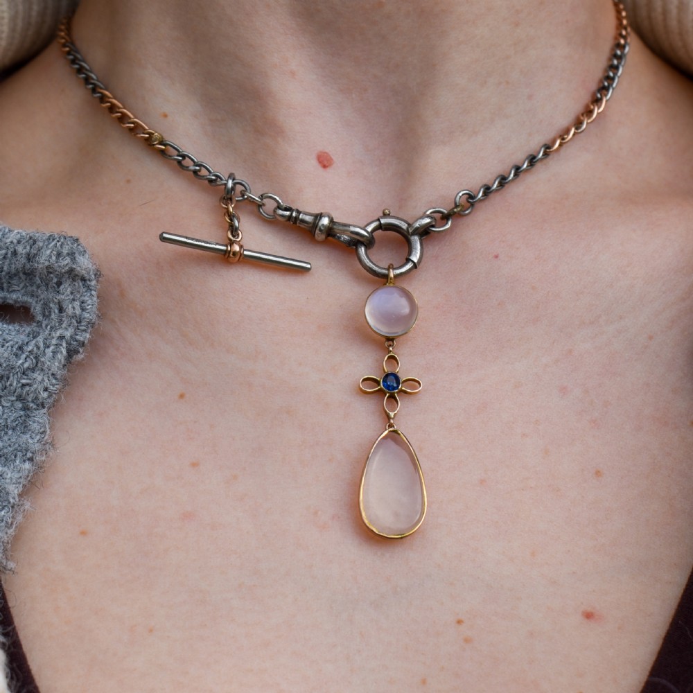 An antique 9ct gold drop pendant featuring a round moonstone cabochon, a centre quatrefoil motif with a blue sapphire, and a teardrop moonstone drop. View IV