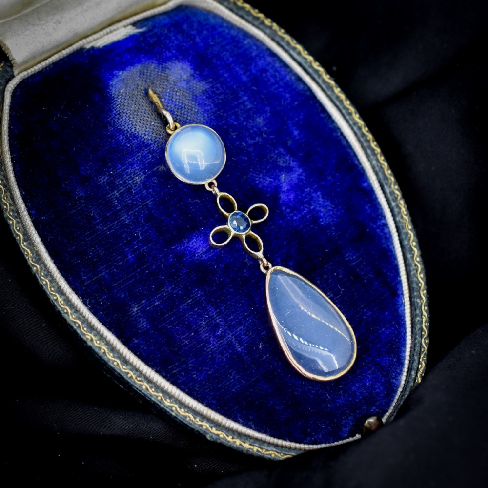 An antique 9ct gold drop pendant featuring a round moonstone cabochon, a centre quatrefoil motif with a blue sapphire, and a teardrop moonstone drop. View VII