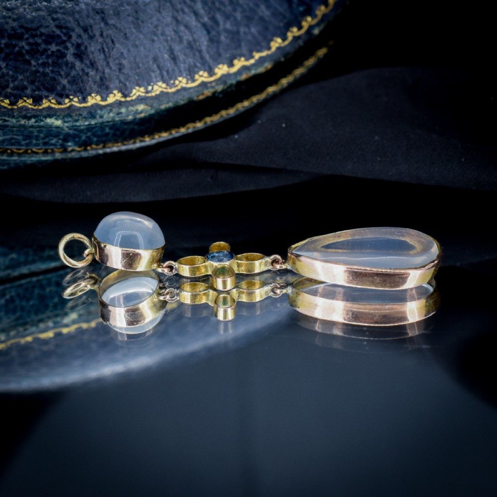 An antique 9ct gold drop pendant featuring a round moonstone cabochon, a centre quatrefoil motif with a blue sapphire, and a teardrop moonstone drop. View VIII