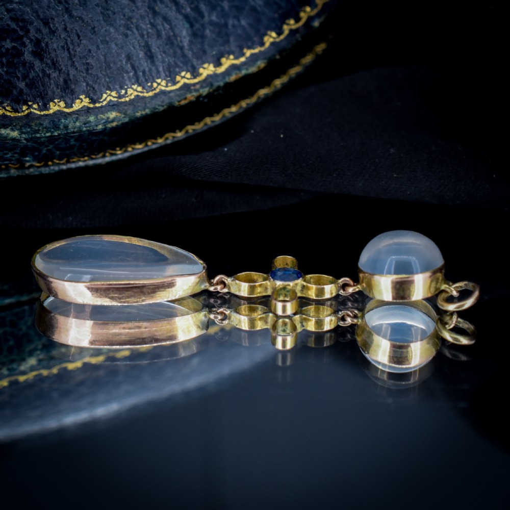 An antique 9ct gold drop pendant featuring a round moonstone cabochon, a centre quatrefoil motif with a blue sapphire, and a teardrop moonstone drop. View IX
