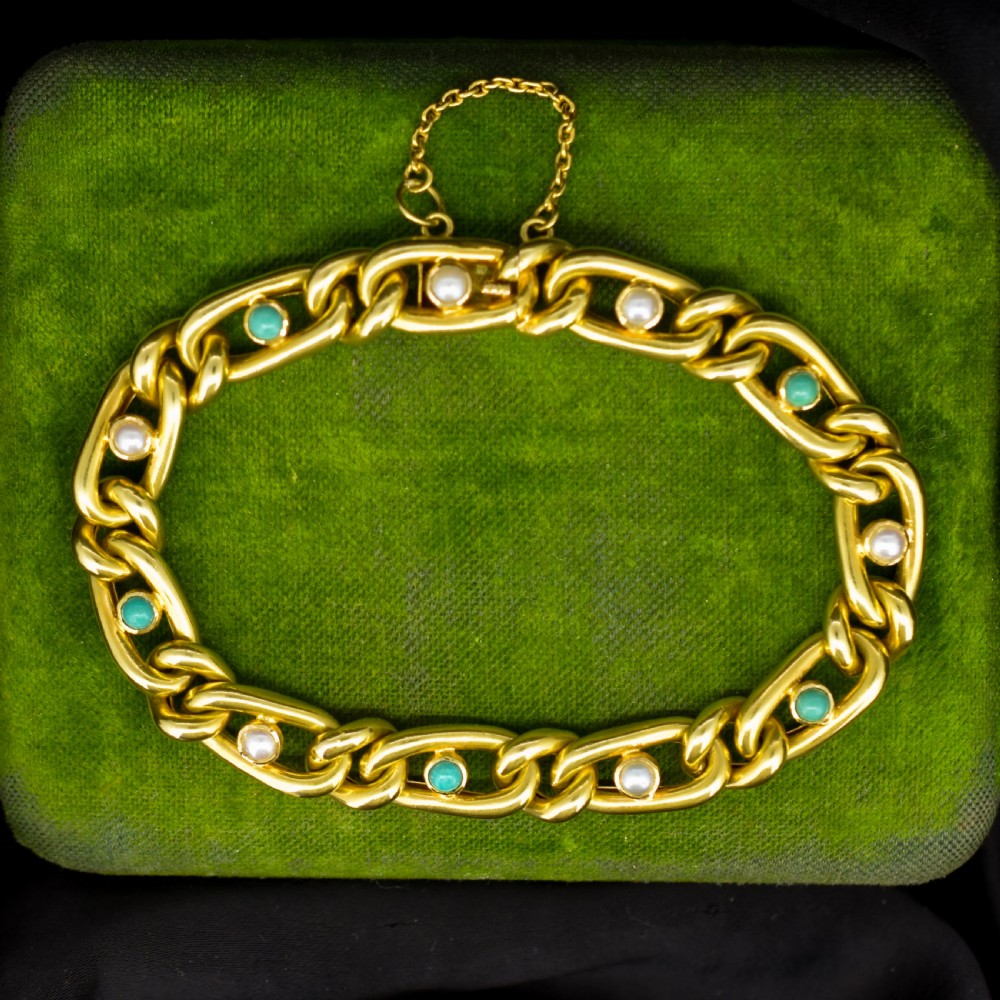 An antique 15ct yellow gold curb link bracelet featuring inset seed pearls and round turquoise cabochons with an attached safety chain.