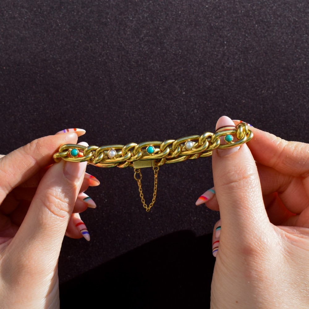An antique 15ct yellow gold curb link bracelet featuring inset seed pearls and round turquoise cabochons with an attached safety chain. View II