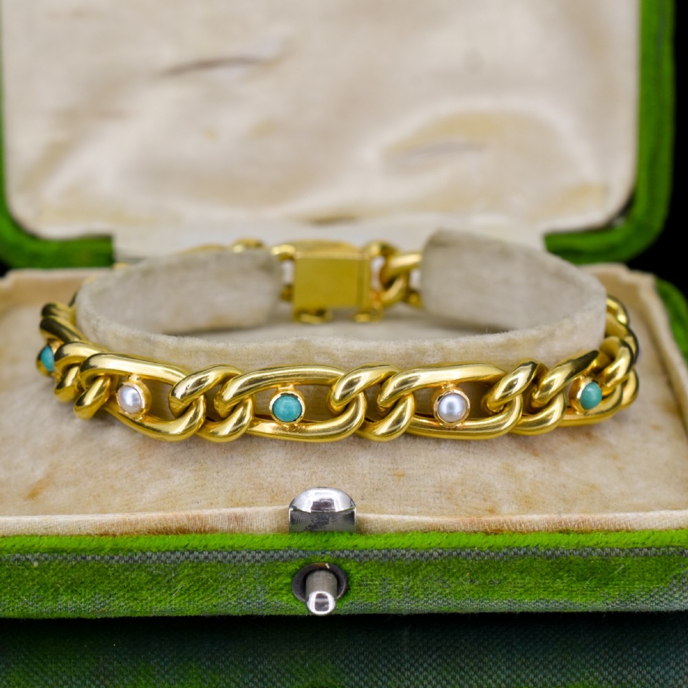 An antique 15ct yellow gold curb link bracelet featuring inset seed pearls and round turquoise cabochons with an attached safety chain. View IV