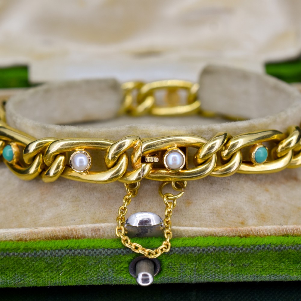 An antique 15ct yellow gold curb link bracelet featuring inset seed pearls and round turquoise cabochons with an attached safety chain. View VII