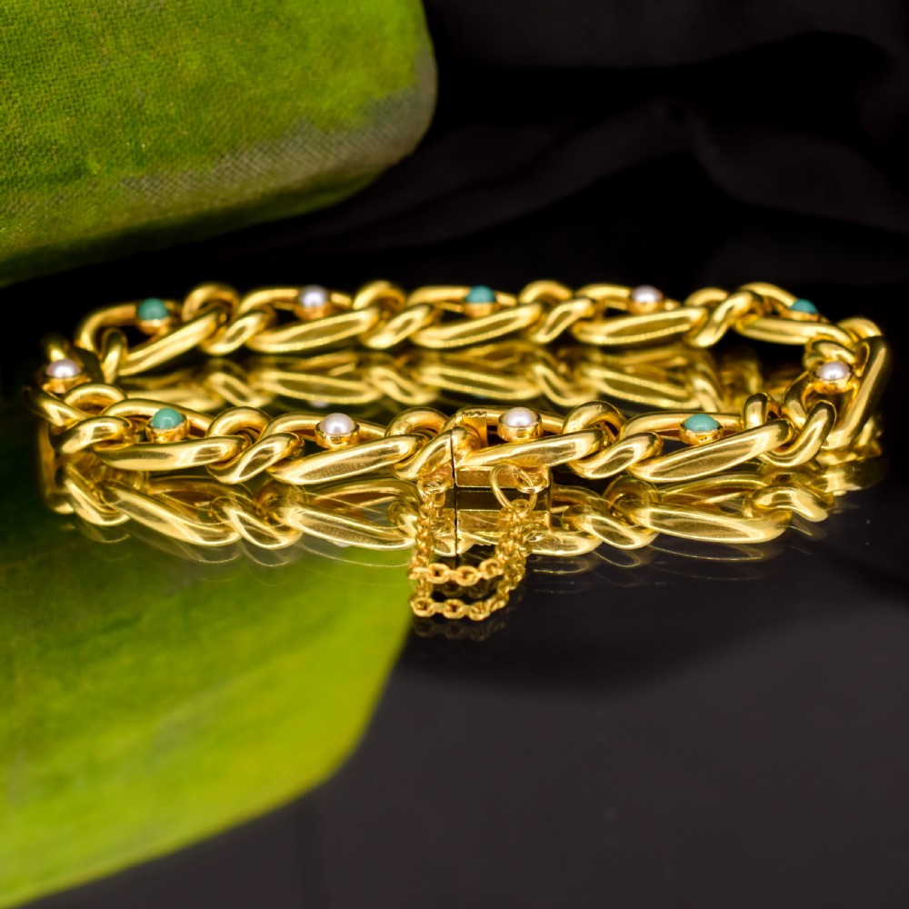 An antique 15ct yellow gold curb link bracelet featuring inset seed pearls and round turquoise cabochons with an attached safety chain. View X