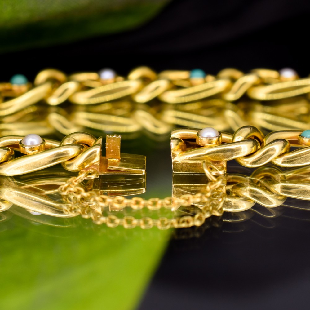 An antique 15ct yellow gold curb link bracelet featuring inset seed pearls and round turquoise cabochons with an attached safety chain. View XI