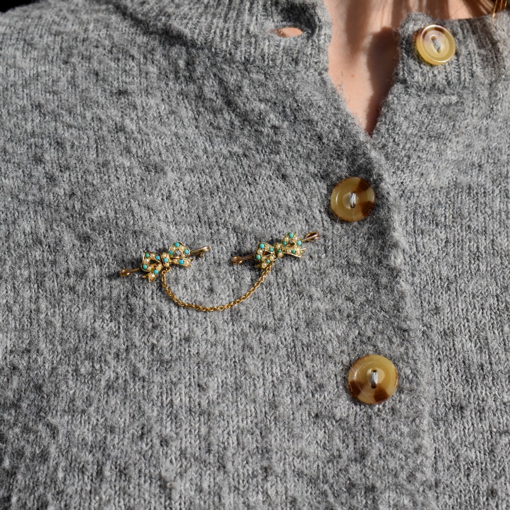 A pair of 15ct gold bow-shaped collar brooches set with seed pearls and turquoise cabochons, linked together by a delicate gold trace chain. View IV