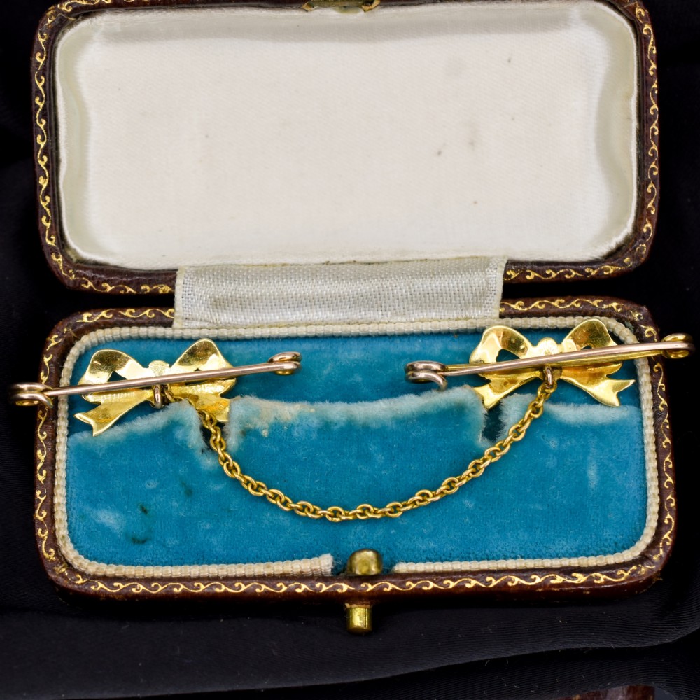 A pair of 15ct gold bow-shaped collar brooches set with seed pearls and turquoise cabochons, linked together by a delicate gold trace chain. View V