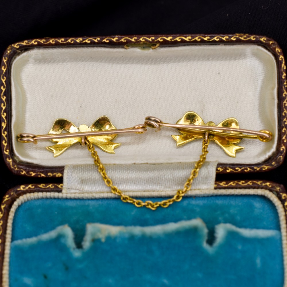 A pair of 15ct gold bow-shaped collar brooches set with seed pearls and turquoise cabochons, linked together by a delicate gold trace chain. View VII