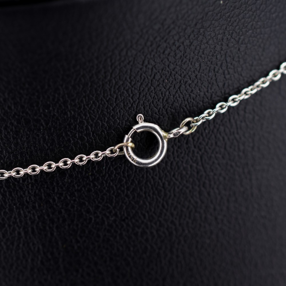 An Art Deco platinum and white gold pendant necklace featuring a bow motif, a heart-shaped opal cabochon, and a tassel drop set with opals and diamonds. View IX