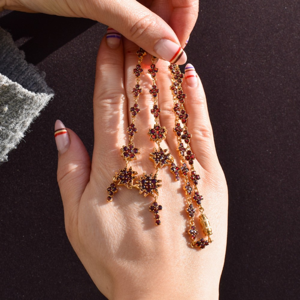 A Victorian gold gilt necklace set with deep red rose-cut Bohemian garnets featuring starburst clusters and drop pendants. View III