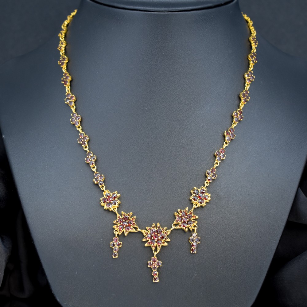 A Victorian gold gilt necklace set with deep red rose-cut Bohemian garnets featuring starburst clusters and drop pendants. View IV