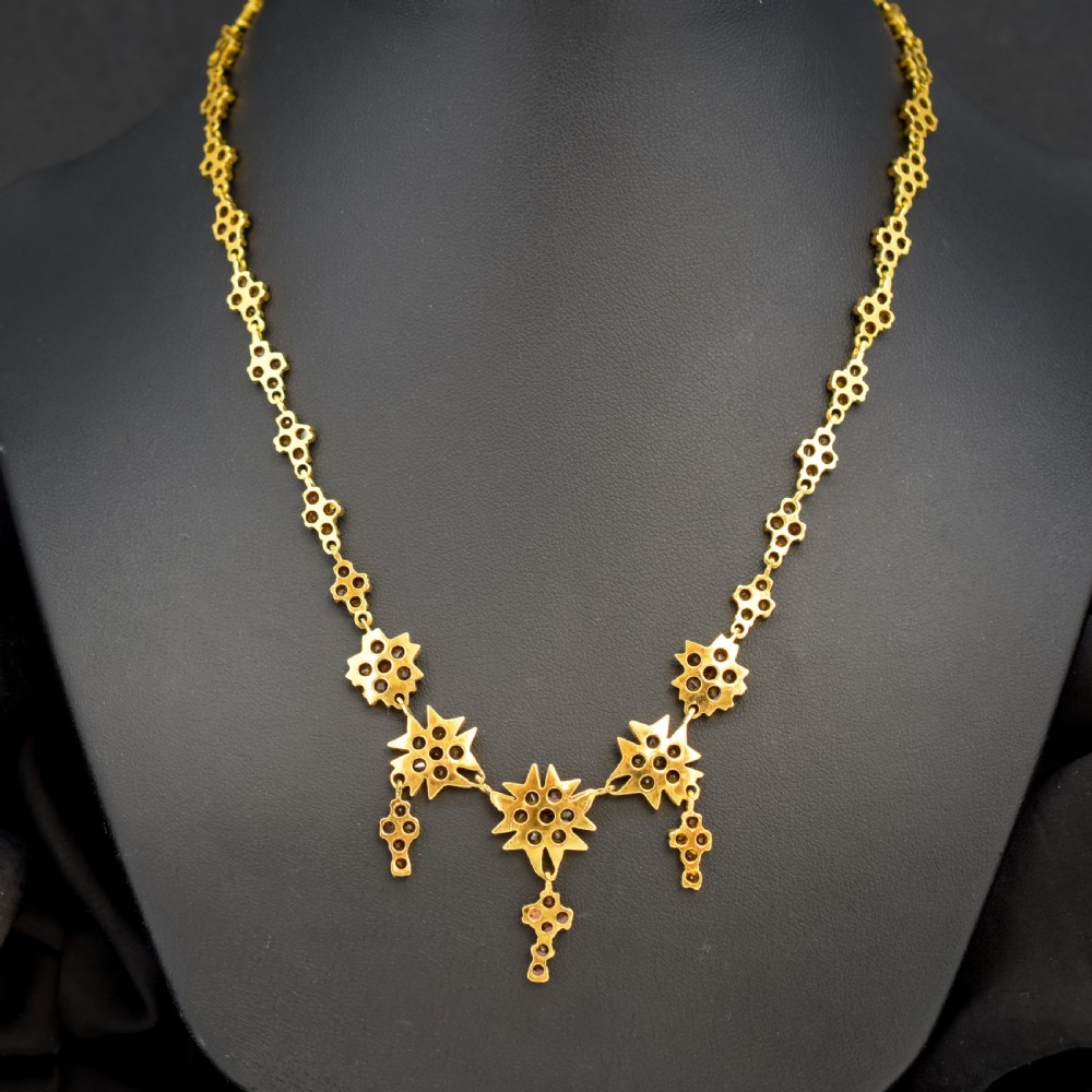 A Victorian gold gilt necklace set with deep red rose-cut Bohemian garnets featuring starburst clusters and drop pendants. View VIII