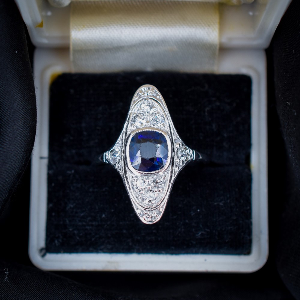 An Art Deco platinum ring featuring a central blue sapphire framed by diamonds within an elongated navette-shaped setting. View V