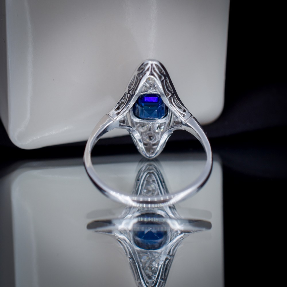 An Art Deco platinum ring featuring a central blue sapphire framed by diamonds within an elongated navette-shaped setting. View IX