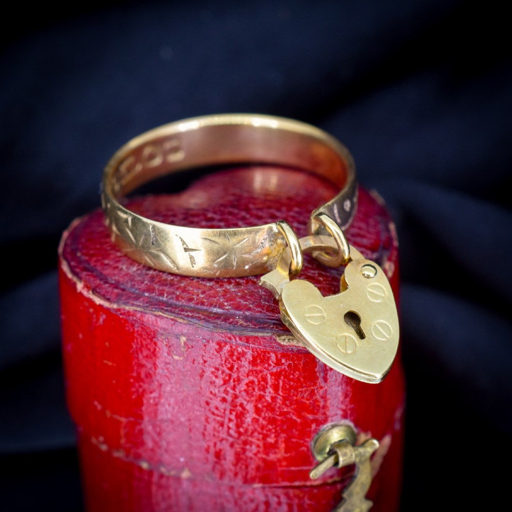 An engraved 9ct yellow gold band featuring a dangling heart padlock charm. View V