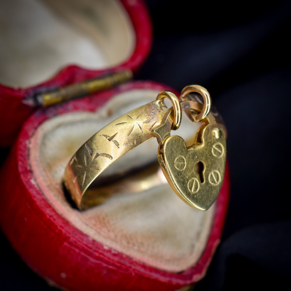 An engraved 9ct yellow gold band featuring a dangling heart padlock charm. View VII