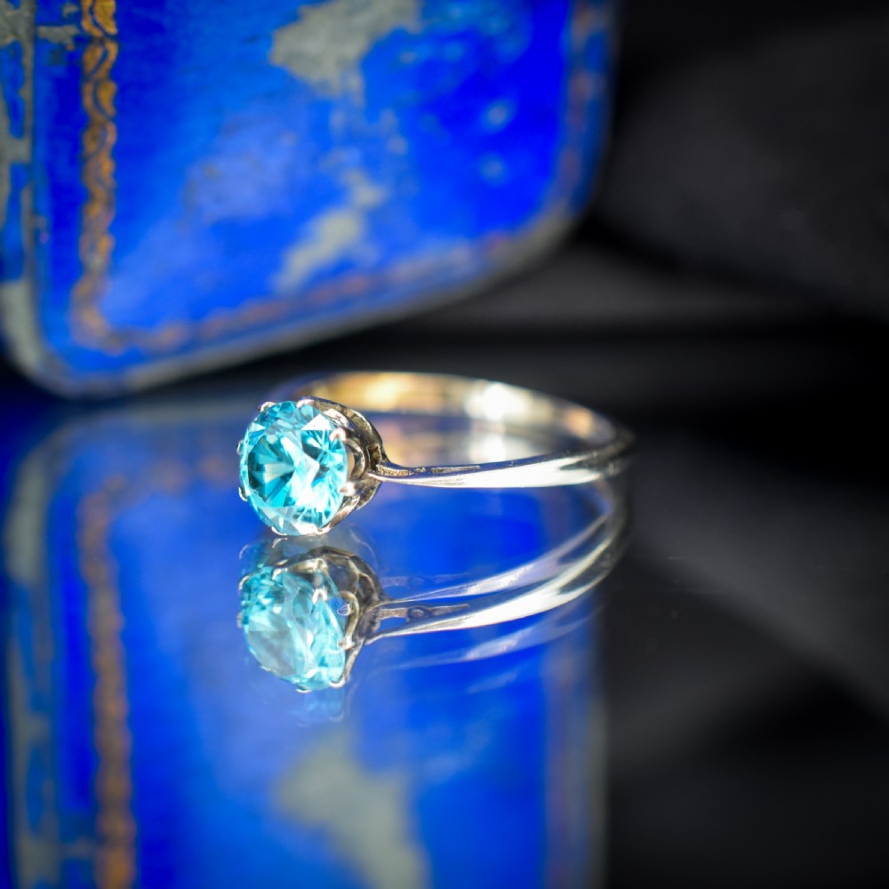 A vintage 9ct gold solitaire ring featuring a brilliant round-cut blue zircon gemstone held in a multi-claw setting. View VI