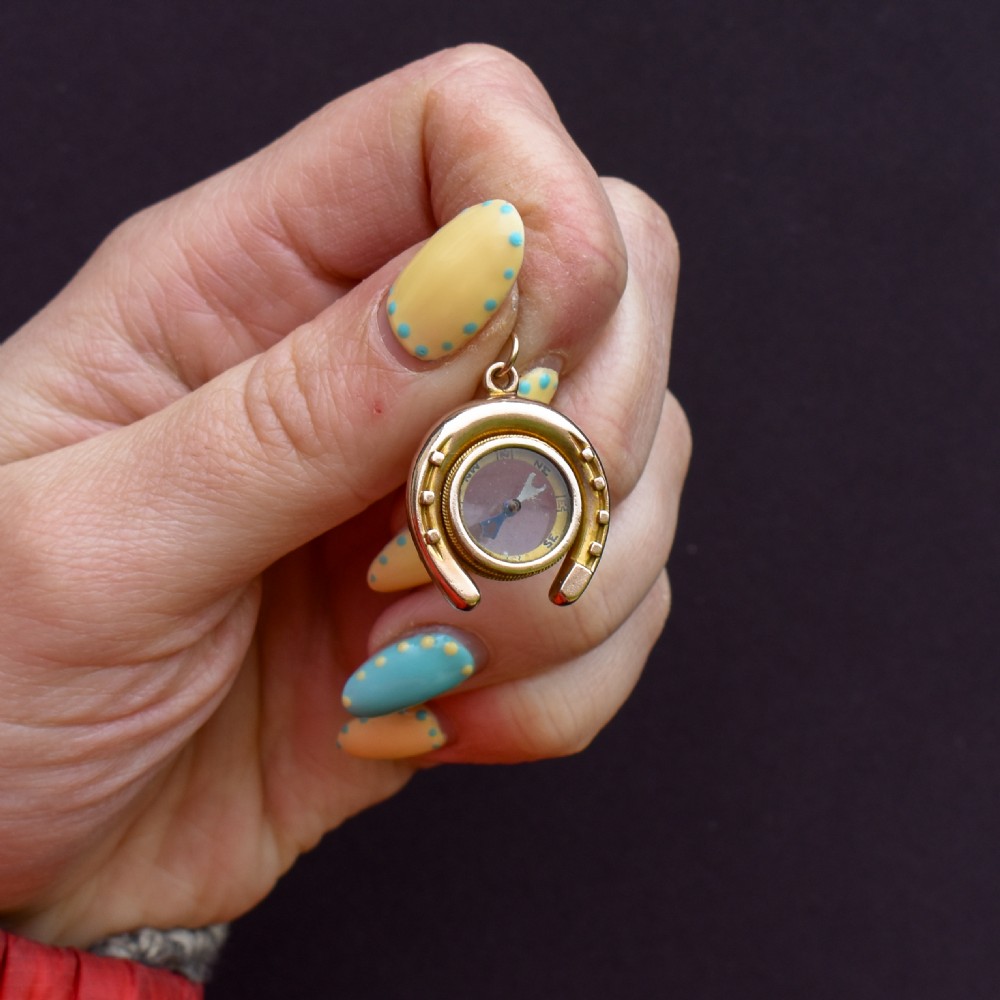 An antique yellow gold horseshoe pendant enclosing a central working compass with a glass face and suspension loop. View II