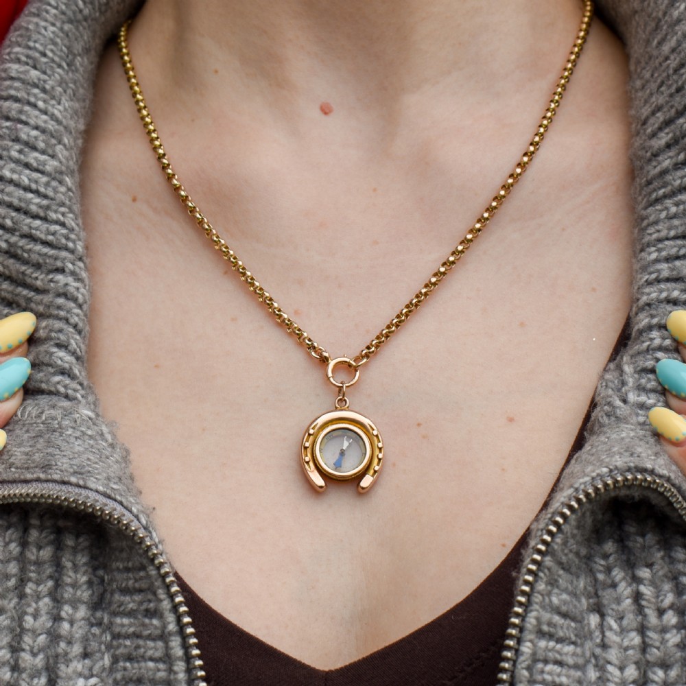 An antique yellow gold horseshoe pendant enclosing a central working compass with a glass face and suspension loop. View III