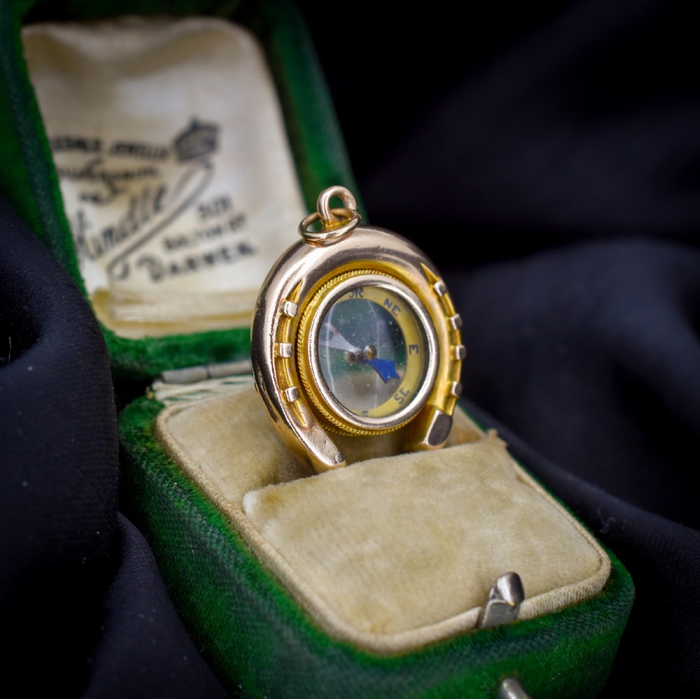 An antique yellow gold horseshoe pendant enclosing a central working compass with a glass face and suspension loop. View V