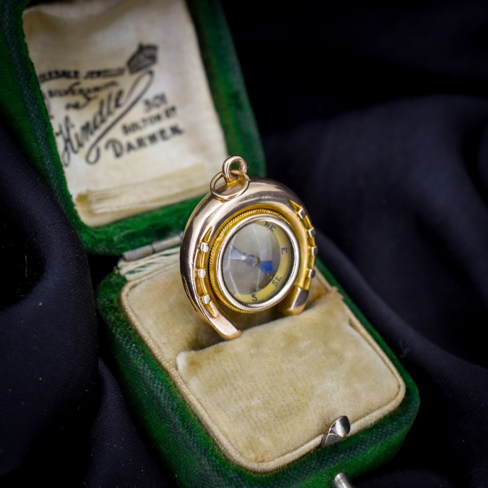 An antique yellow gold horseshoe pendant enclosing a central working compass with a glass face and suspension loop. View VII