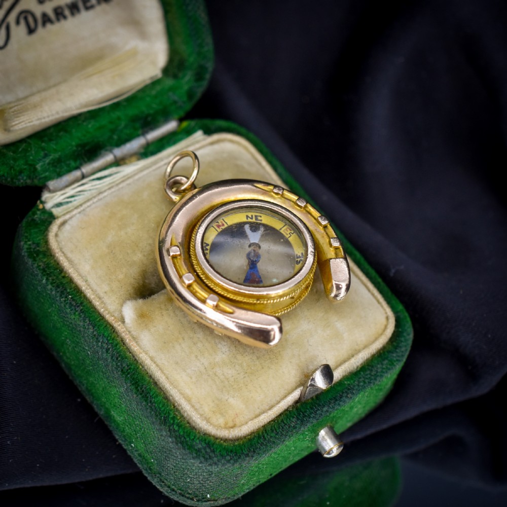 An antique yellow gold horseshoe pendant enclosing a central working compass with a glass face and suspension loop. View VIII