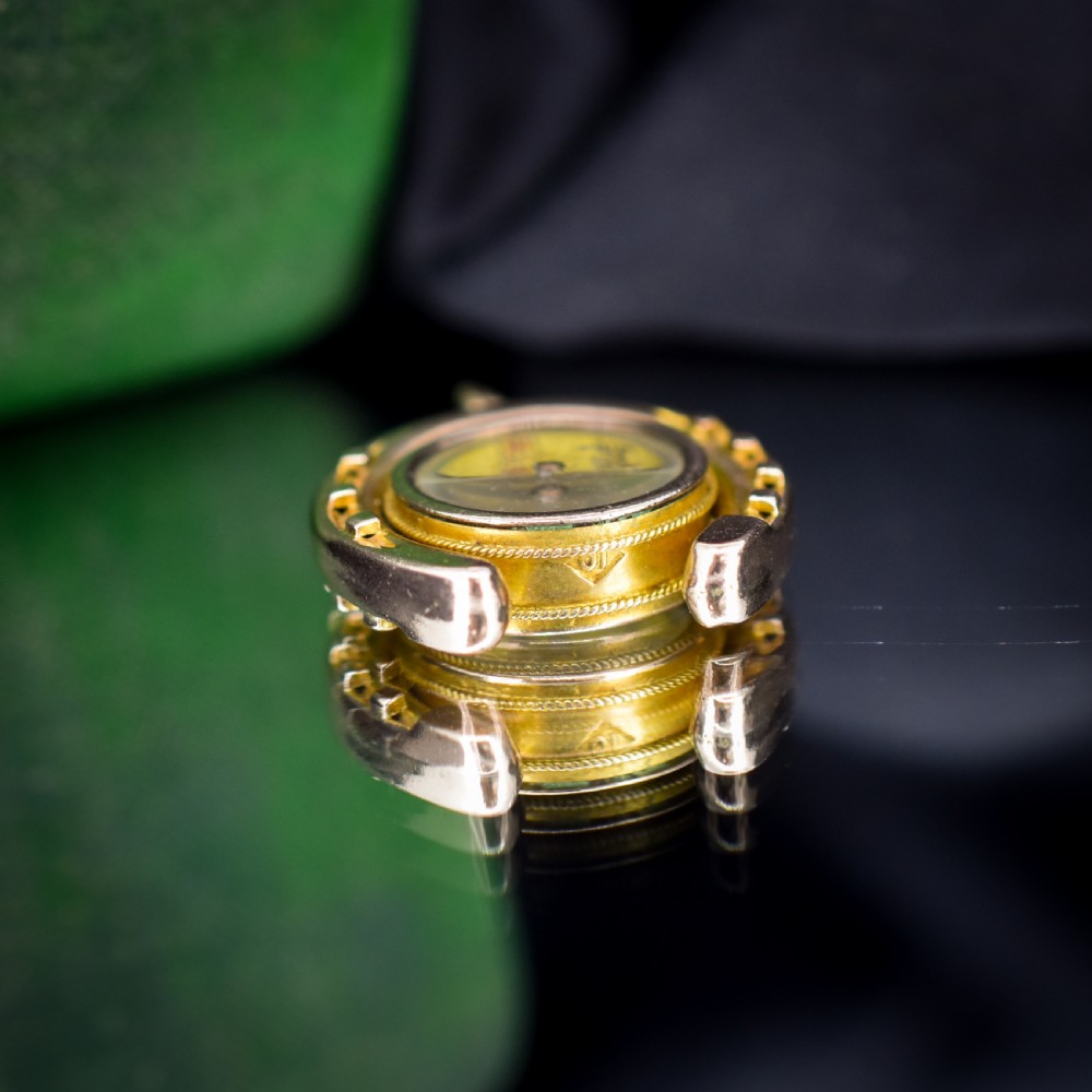 An antique yellow gold horseshoe pendant enclosing a central working compass with a glass face and suspension loop. View X