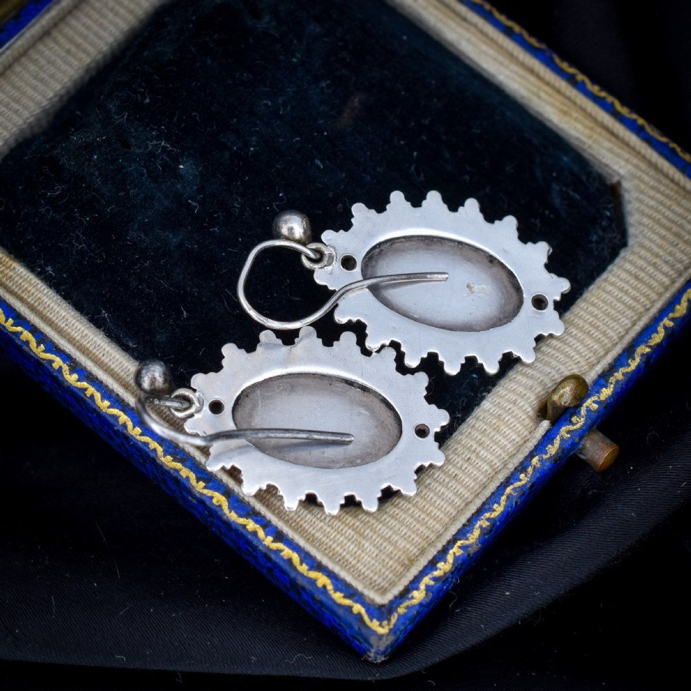 A pair of oval sterling silver Victorian Aesthetic Movement drop earrings featuring engraved geometric and botanical designs with beaded borders. View VII