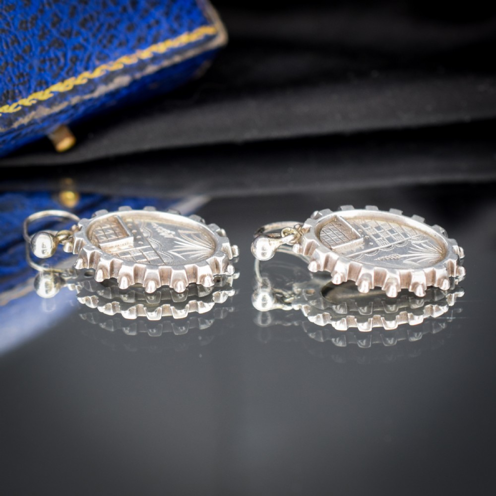 A pair of oval sterling silver Victorian Aesthetic Movement drop earrings featuring engraved geometric and botanical designs with beaded borders. View IX