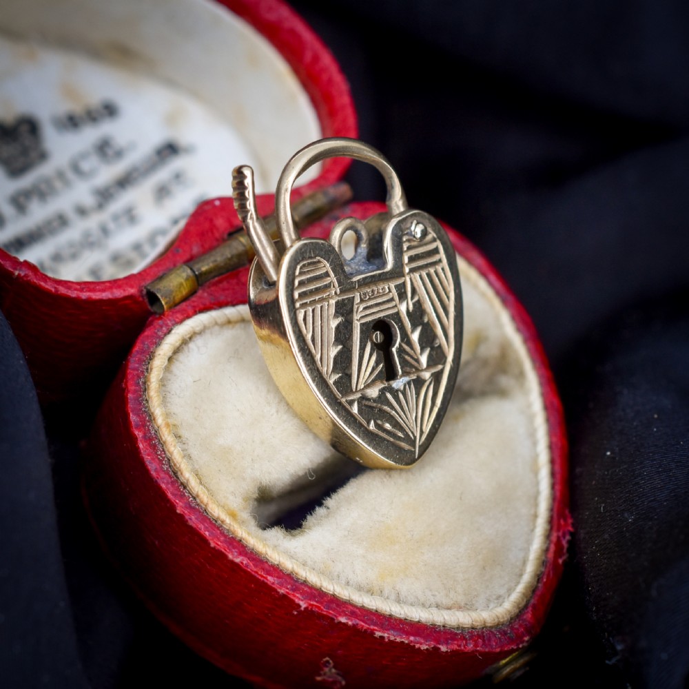 A vintage 9ct yellow gold heart-shaped padlock charm with geometric and botanical hand-engraved patterns and a keyhole detail. View III