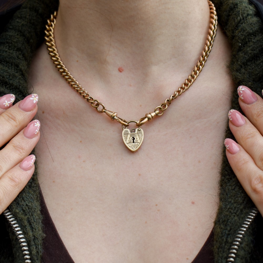 A vintage 9ct yellow gold heart-shaped padlock charm with geometric and botanical hand-engraved patterns and a keyhole detail. View IV