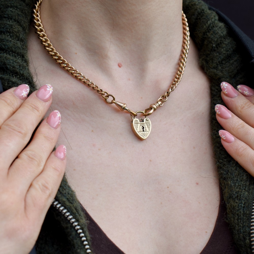 A vintage 9ct yellow gold heart-shaped padlock charm with geometric and botanical hand-engraved patterns and a keyhole detail. View VI
