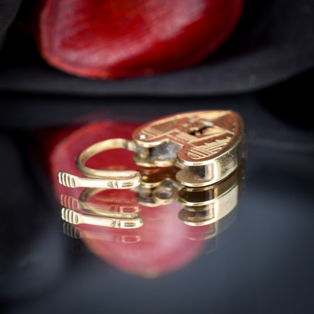 A vintage 9ct yellow gold heart-shaped padlock charm with geometric and botanical hand-engraved patterns and a keyhole detail. View X