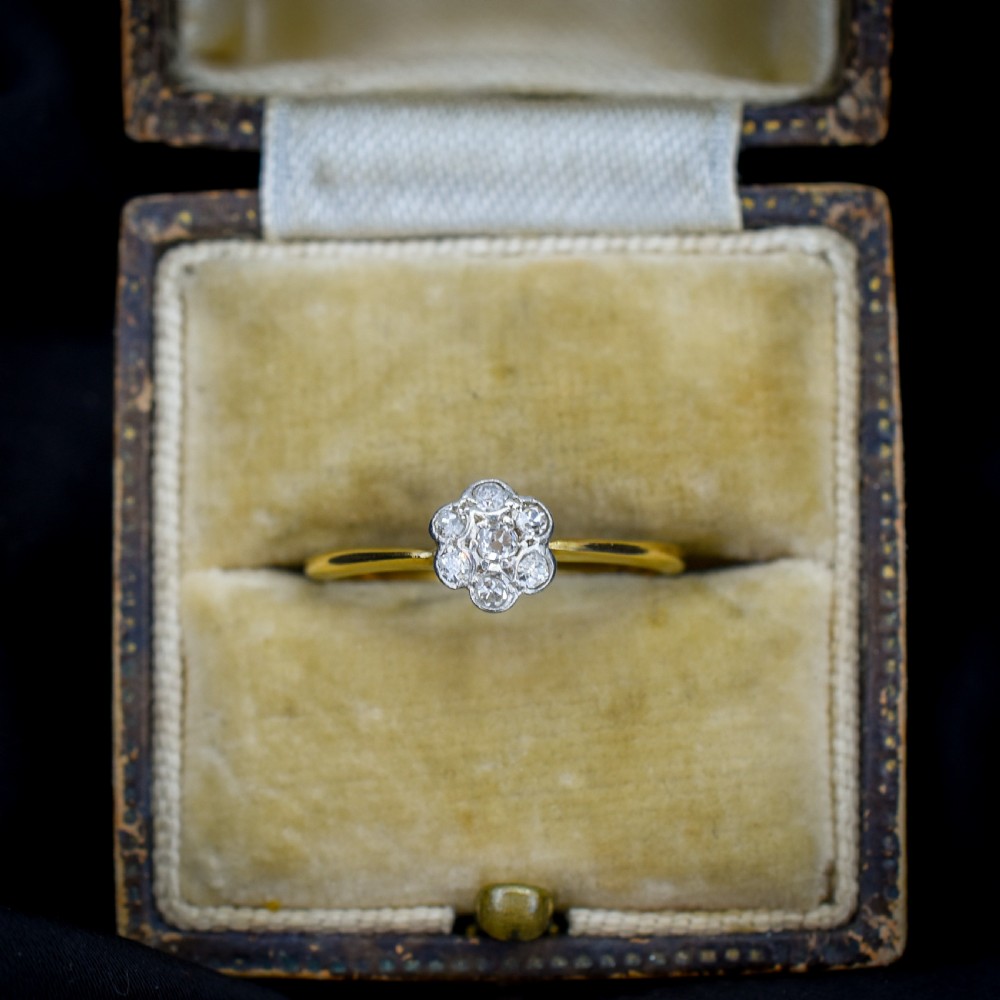 An 18ct yellow gold ring featuring a floral diamond cluster head set in white metal.