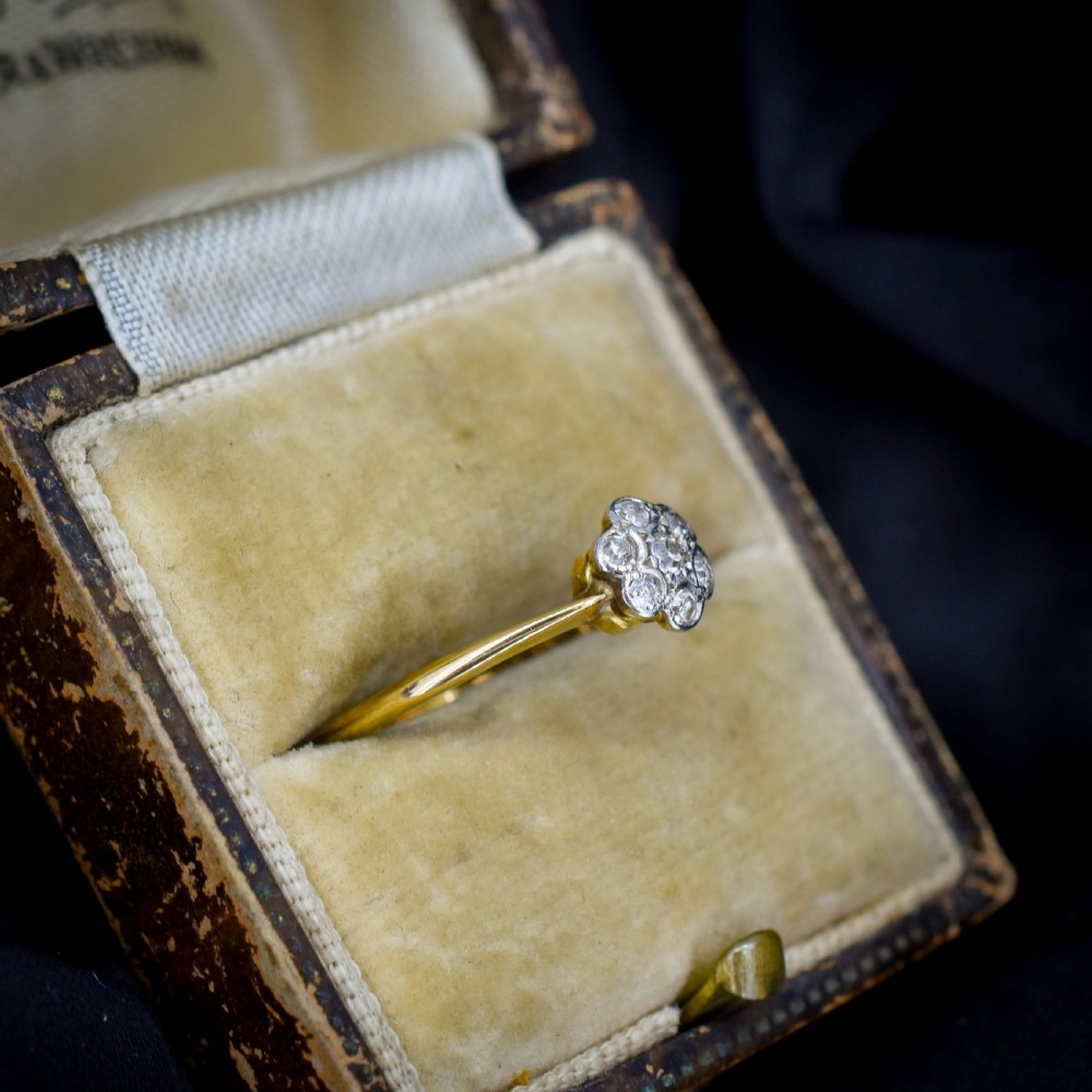 An 18ct yellow gold ring featuring a floral diamond cluster head set in white metal. View V