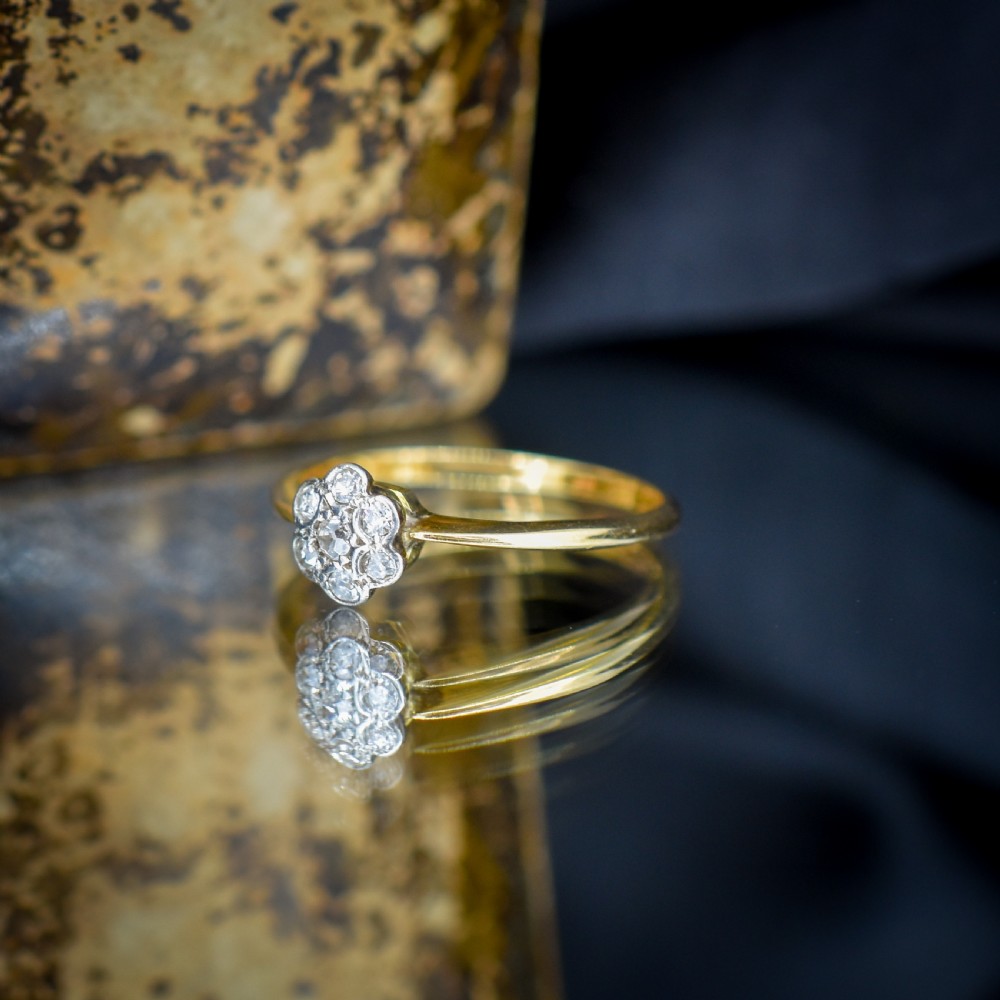 An 18ct yellow gold ring featuring a floral diamond cluster head set in white metal. View IX