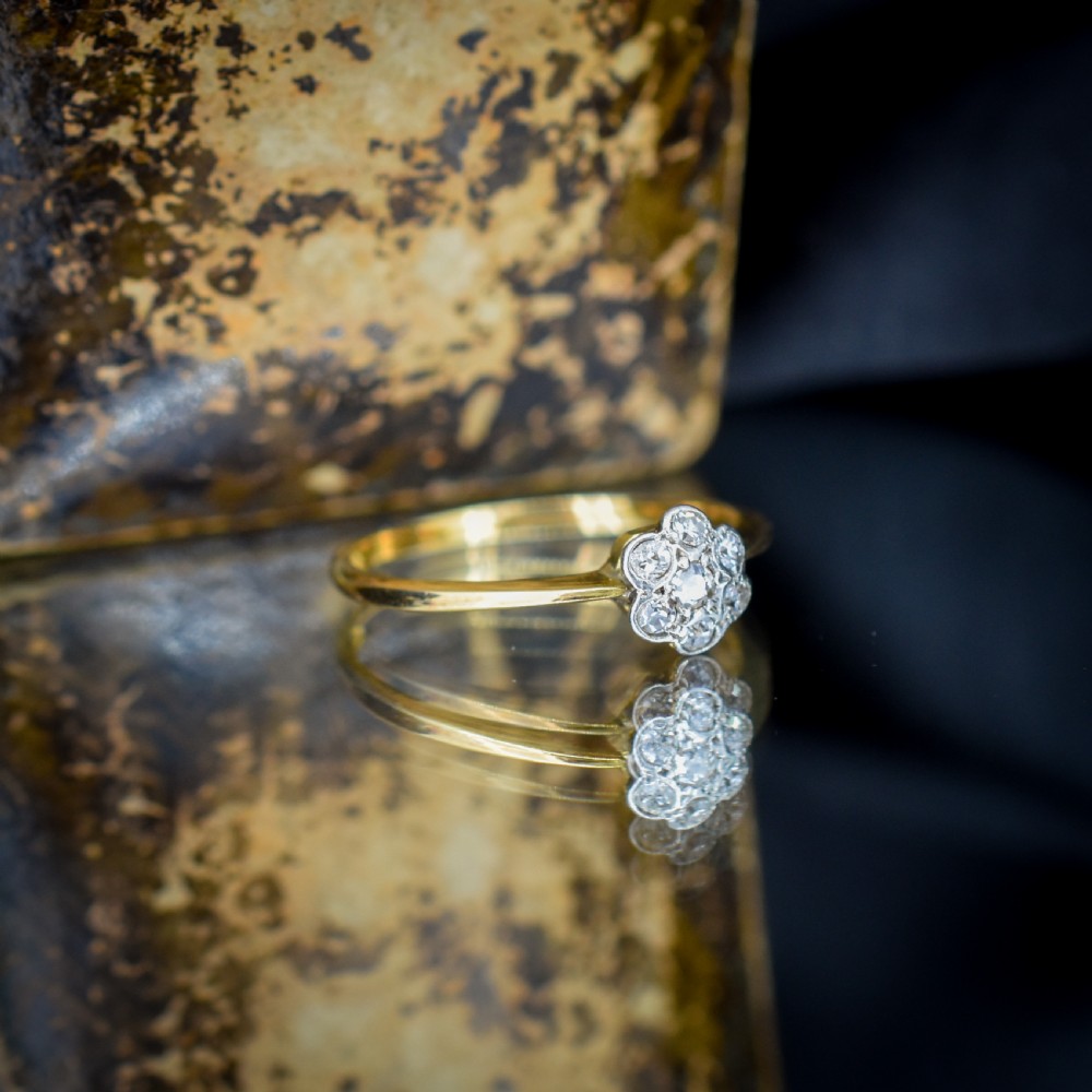 An 18ct yellow gold ring featuring a floral diamond cluster head set in white metal. View X